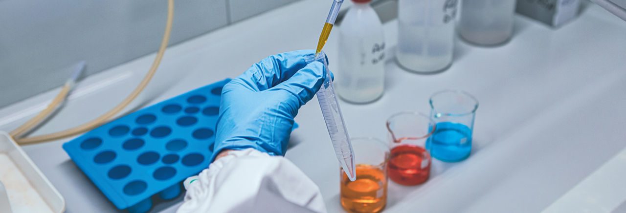 Dipendente Iren in un laboratorio analizza dei campioni di liquido con focus sulle mani