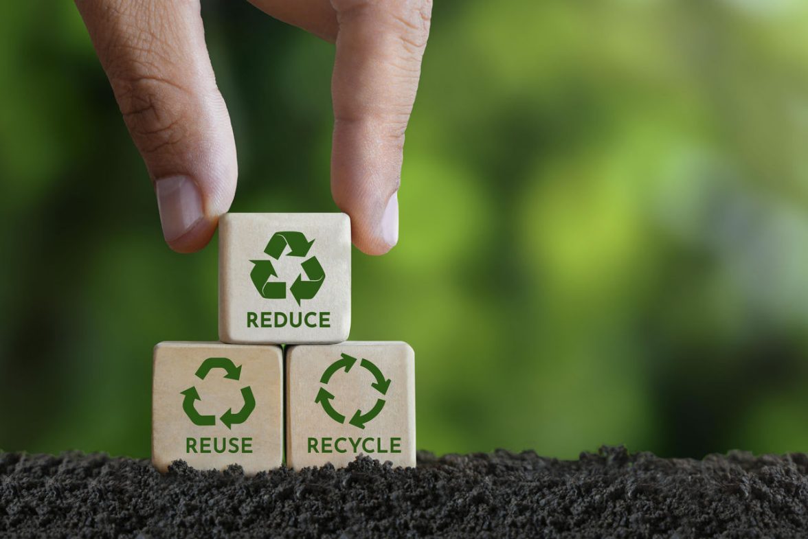 una piramide composta da tre cubi di legno, con una mano che mettere al vertice l'ultimo cubo, gli altri poggiati sulla terra; sui cubi c'è scritto rispettivamente: reduce, reuse, recycle