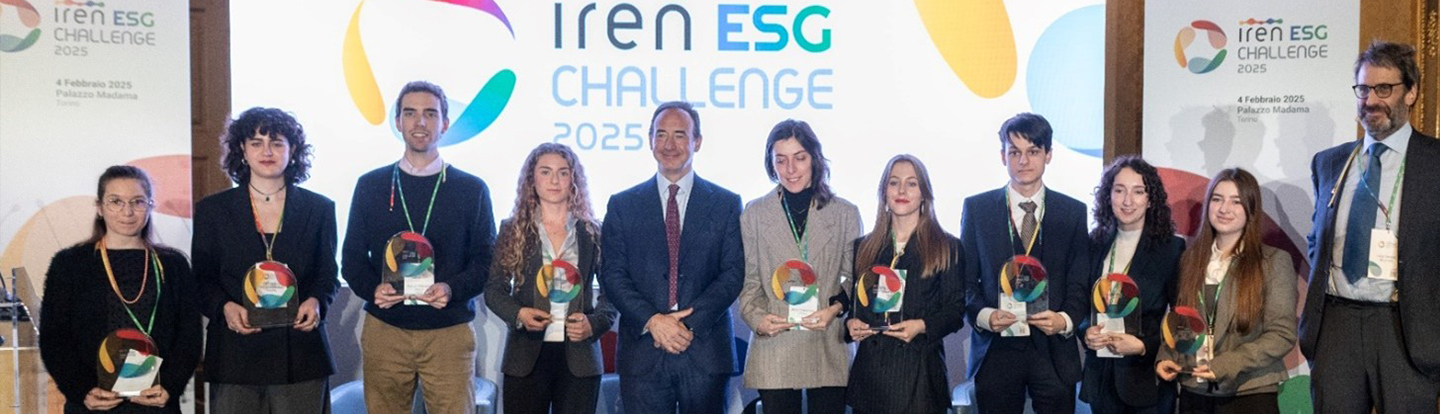 Un gruppo di dieci giovani vincitori posa con i trofei in mano accanto a due uomini in abito durante l'evento "Iren ESG Challenge 2025" a Palazzo Madama, Torino. Sullo sfondo, il logo dell'evento è visibile su uno schermo e un banner, accompagnato da elementi grafici colorati.