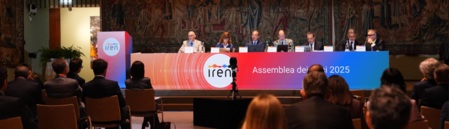 Veduta dell’assemblea dei soci Iren 2025: i membri del CdA siedono al tavolo principale mentre il pubblico segue l’intervento. Sullo sfondo, il maxischermo proietta uno dei relatori in primo piano.