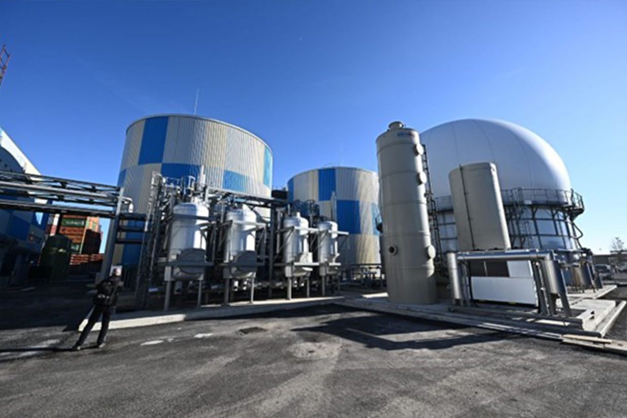 Una struttura industriale moderna con grandi silos e impianti tecnologici all'aperto sotto un cielo sereno.