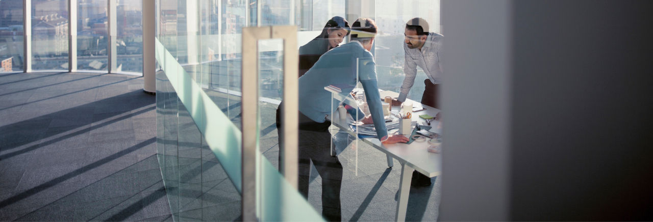Persone raccolte ad un tavolo in riunione dietro ad una vetrata trasparente
