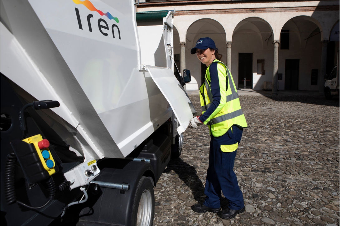 Operatrice ecologica Iren accanto ad un mezzo per la pulizia delle strade