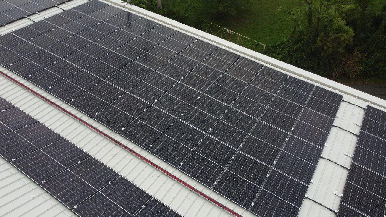 Vista dall'alto di un tetto di un edificio industriale su cui ci sono una serie di pannelli fotovoltaici